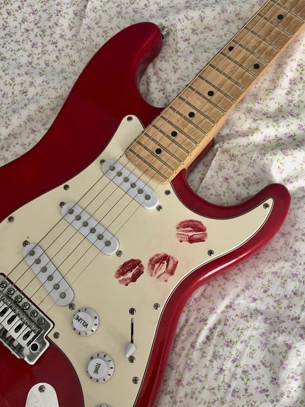 red guitar on a bed.